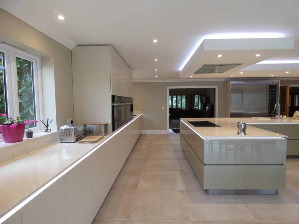 handleless cream gloss kitchen with lights under the counter tops. With fully integrated appliances.